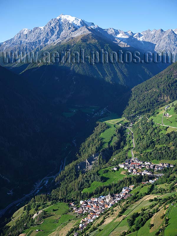 AERIAL VIEW photo of The village of Stilfs with the Stelvio Massif in the distance. Trentino-Alto Adige, Italy.