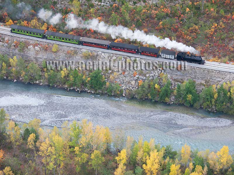 Aerial view of a historic steam strain known as Train des Pignes alongside a river in the French Alps. Vue aérienne.