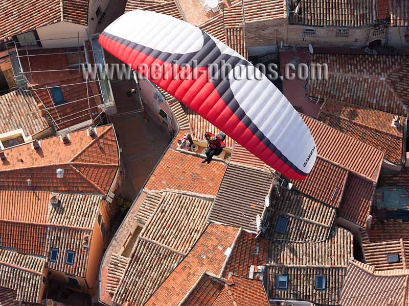 AERIAL VIEW photo of a paraglider flying above roofs, Roquebrune-Cap-Martin, French Riviera, France. VUE AERIENNE parapente survolant des toits, Côte d'Azur.